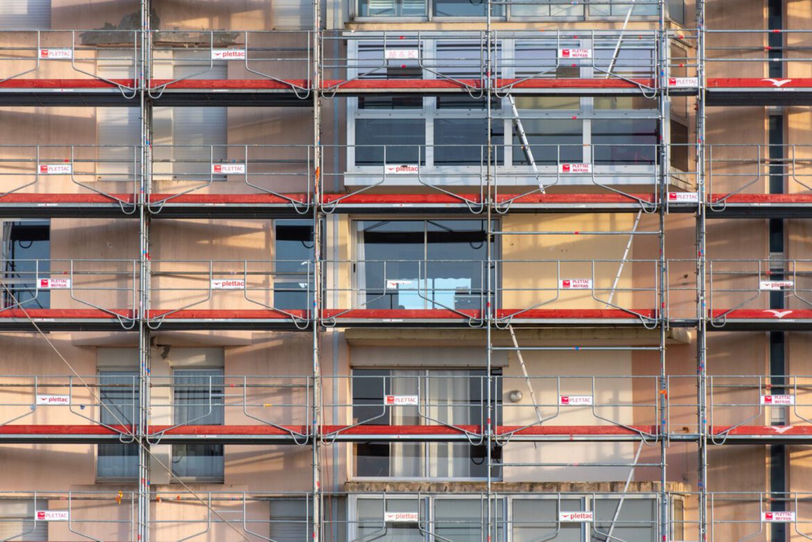 Scaffolding covers an urban building facade, capturing a construction site in detail.