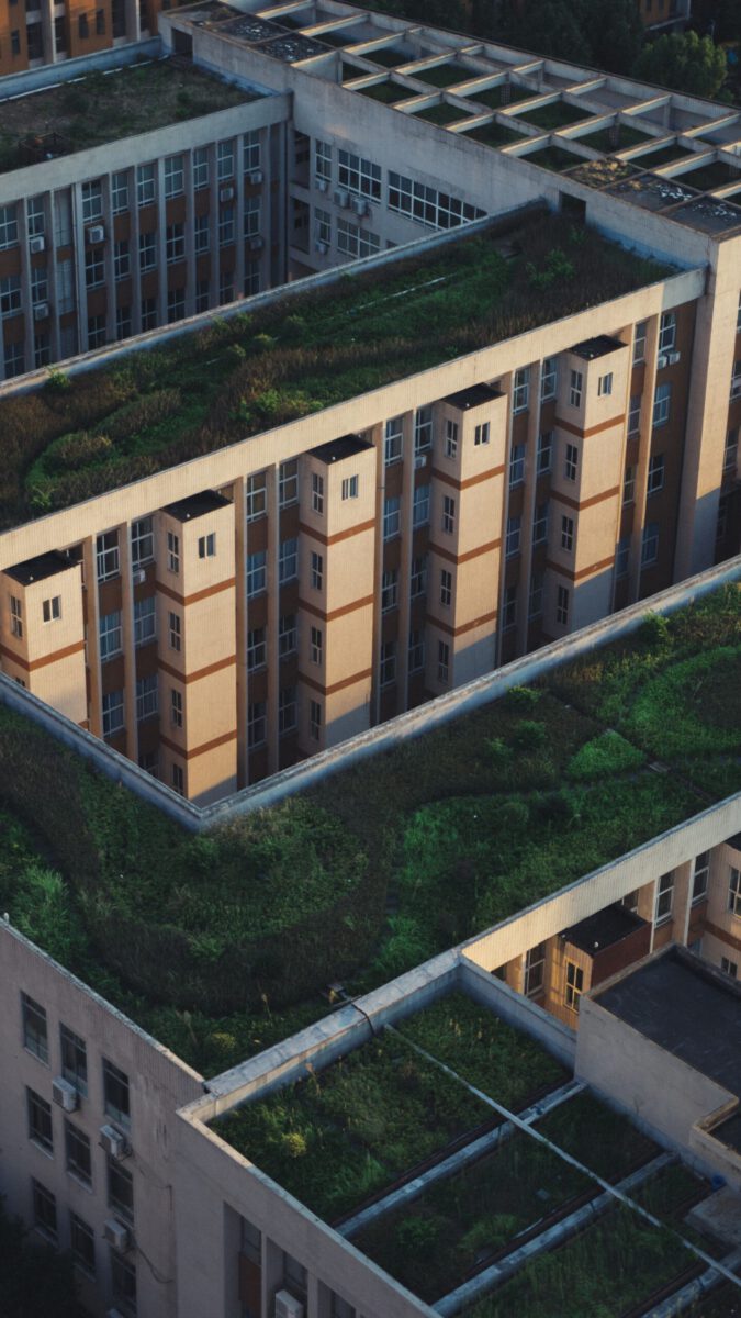 Aerial shot showcasing green rooftop gardens amidst urban buildings, promoting eco-friendly architecture.